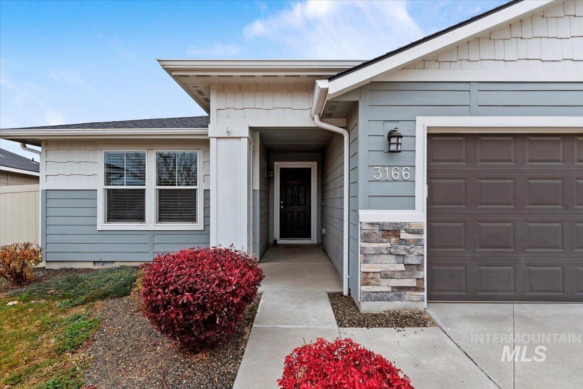 Doorway to property featuring an attached garage and stone siding