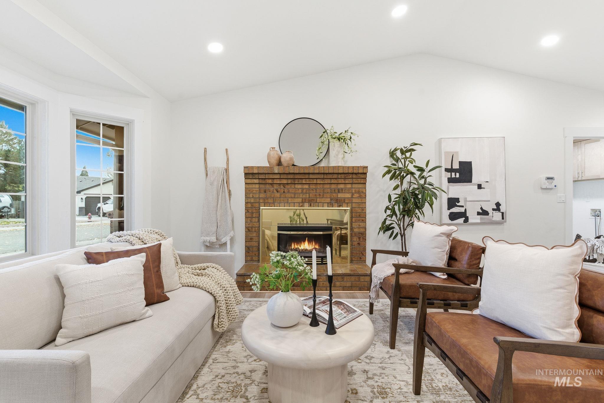 Living area with vaulted ceiling, a brick fireplace, recessed lighting, and wood finished floors