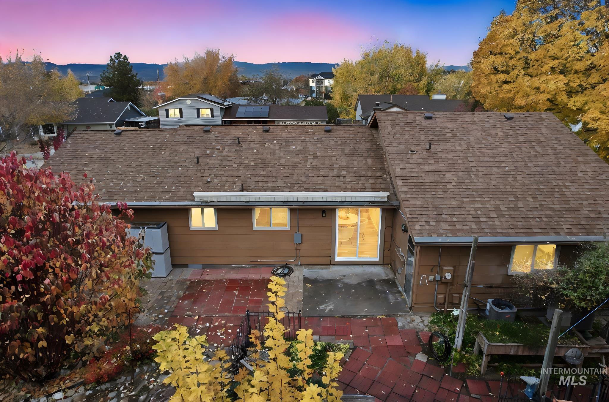 Back of house at dusk featuring a patio area and roof with shingles