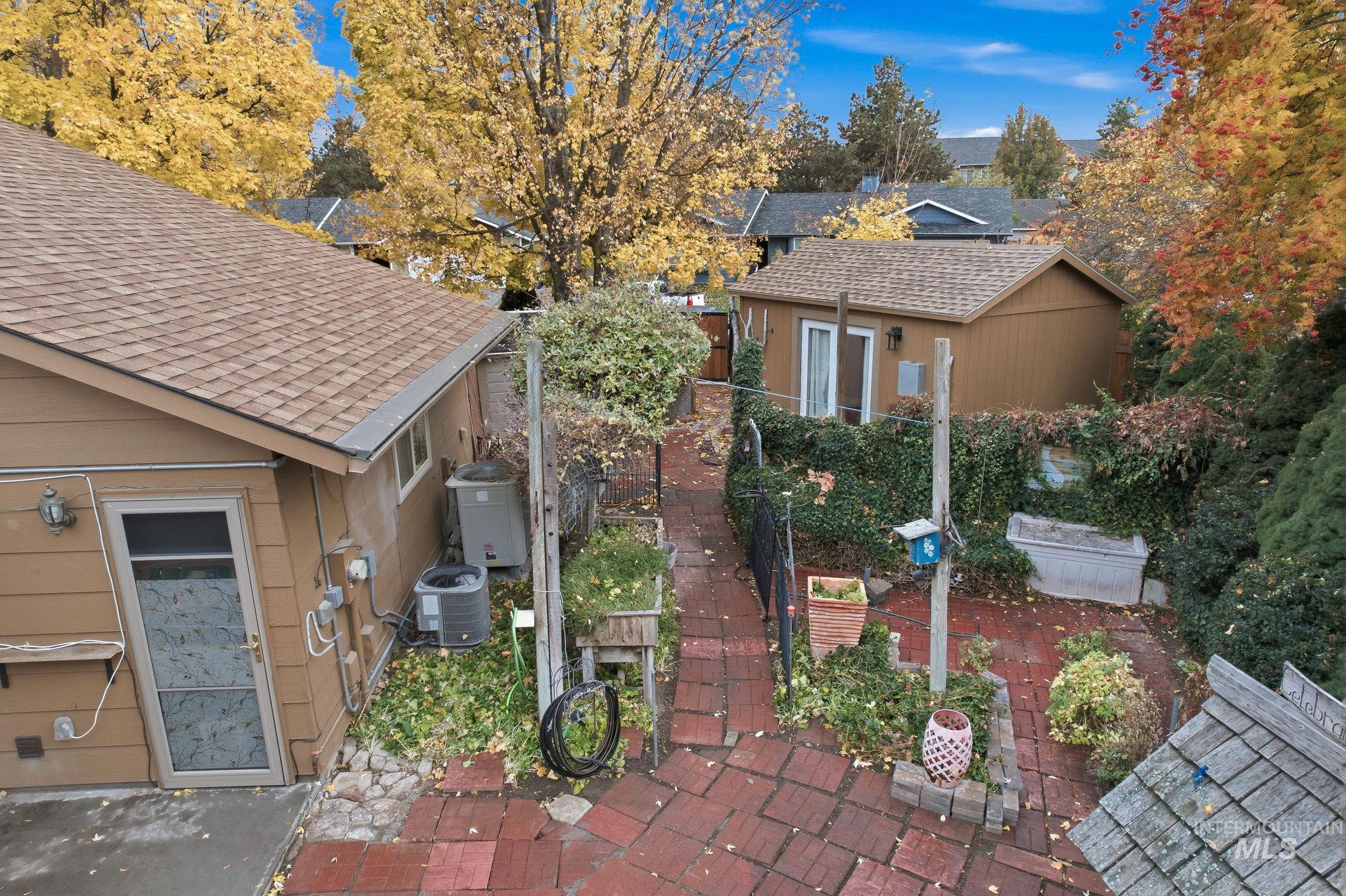 View of property exterior with a shingled roof, a patio, and a garden