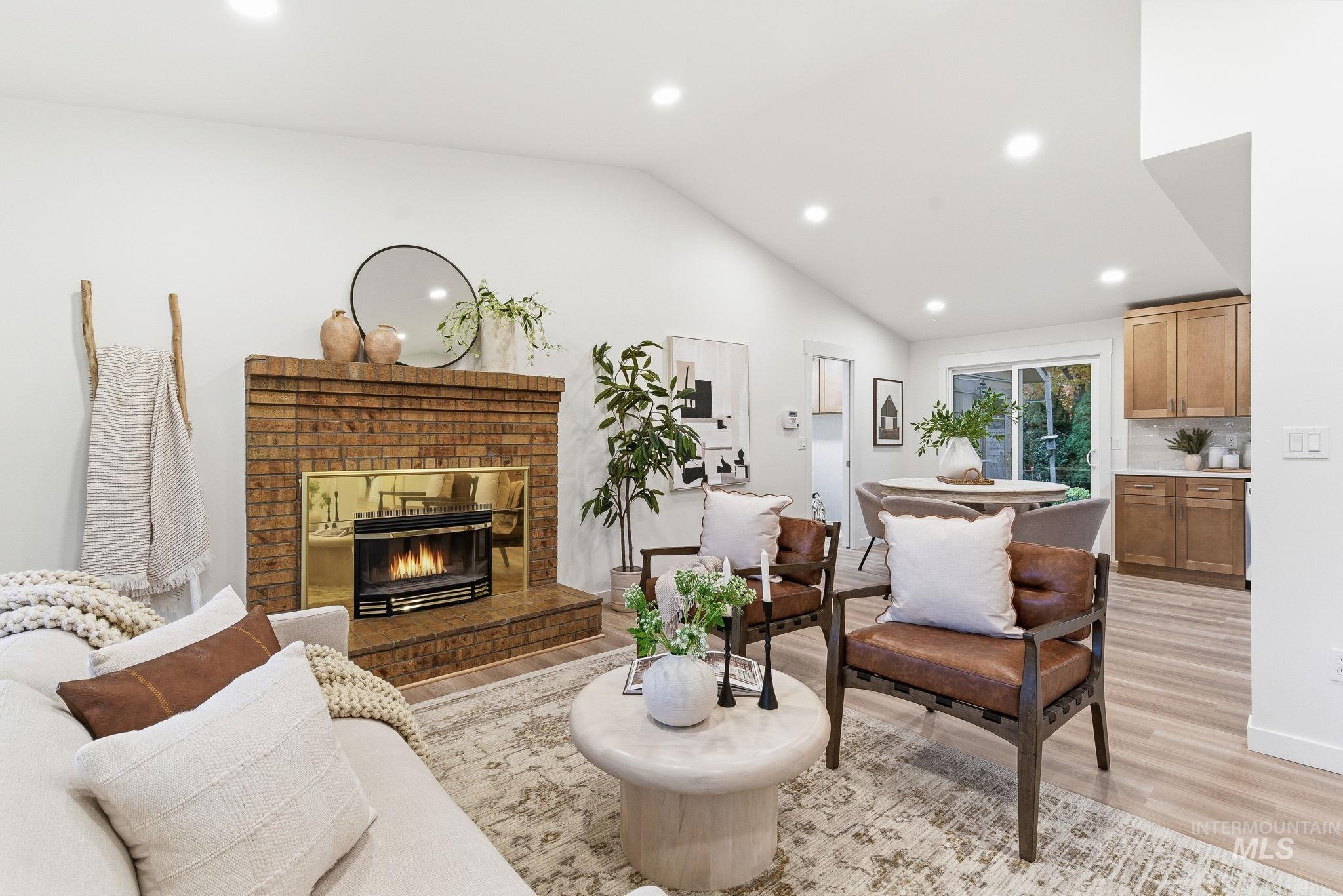 Living area featuring recessed lighting, light wood finished floors, vaulted ceiling, and a brick fireplace