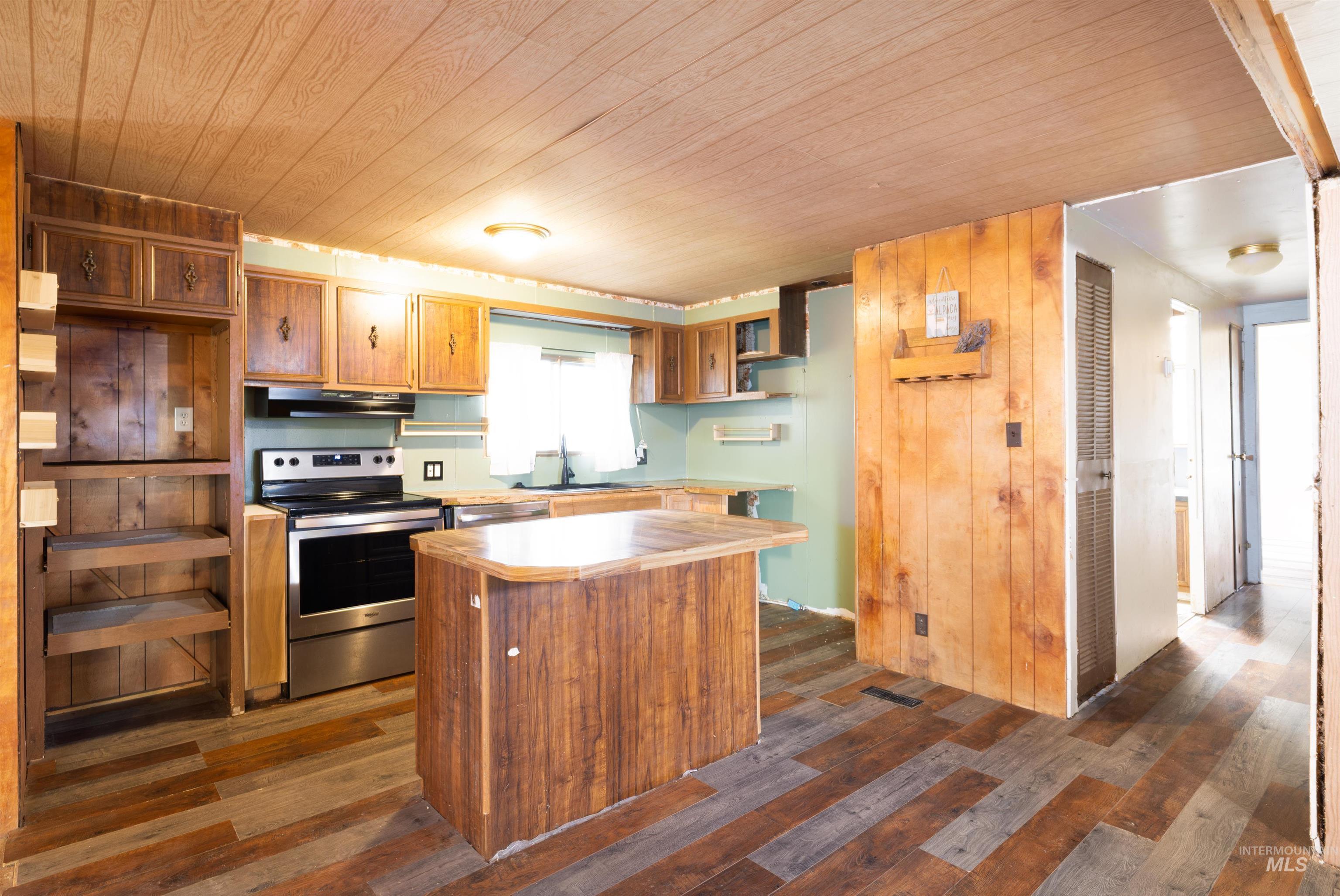Kitchen with open shelves, light countertops, a center island, stainless steel appliances, and dark wood finished floors