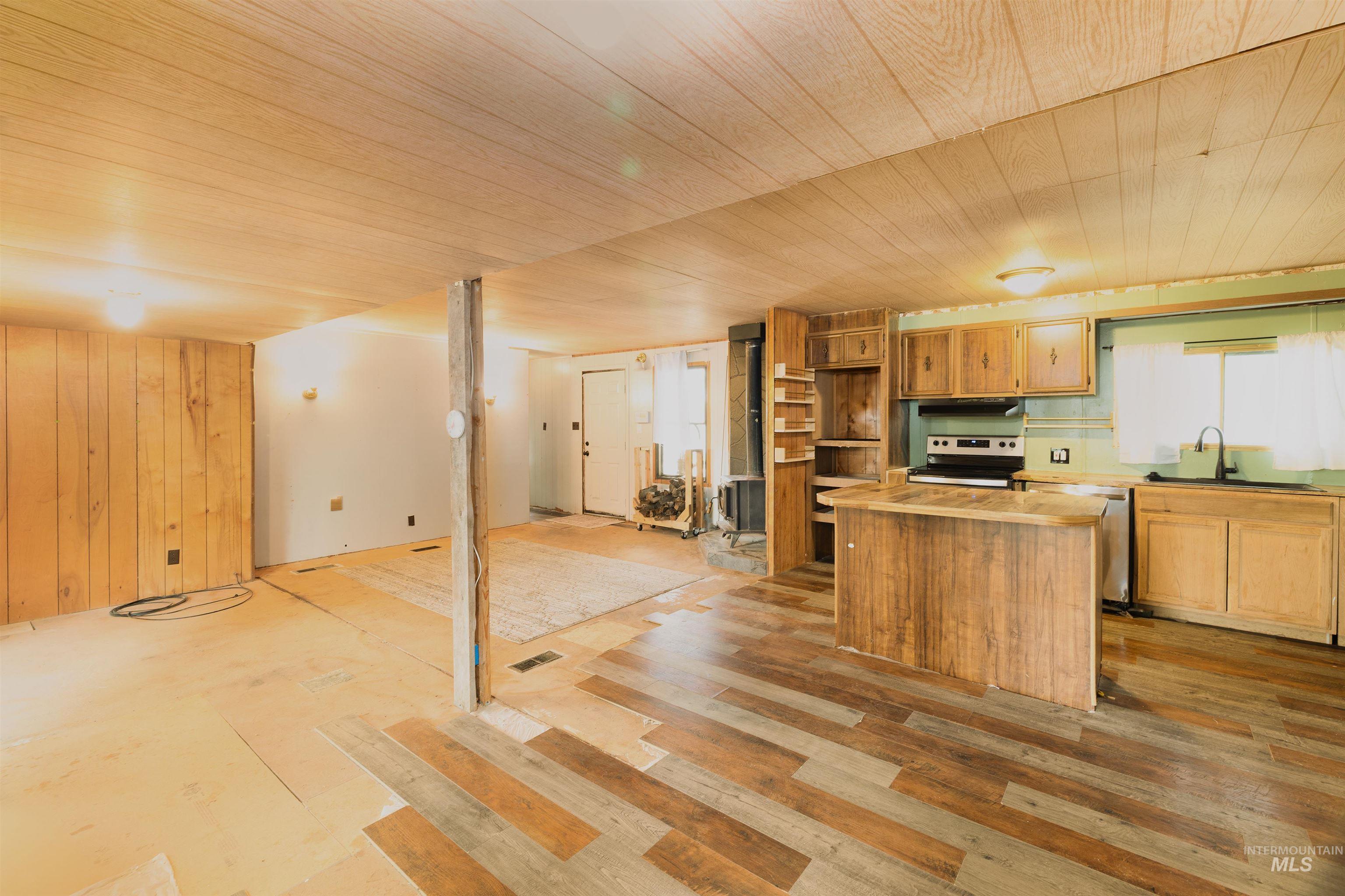 Kitchen with open floor plan, appliances with stainless steel finishes, open shelves, wooden walls, and a kitchen island