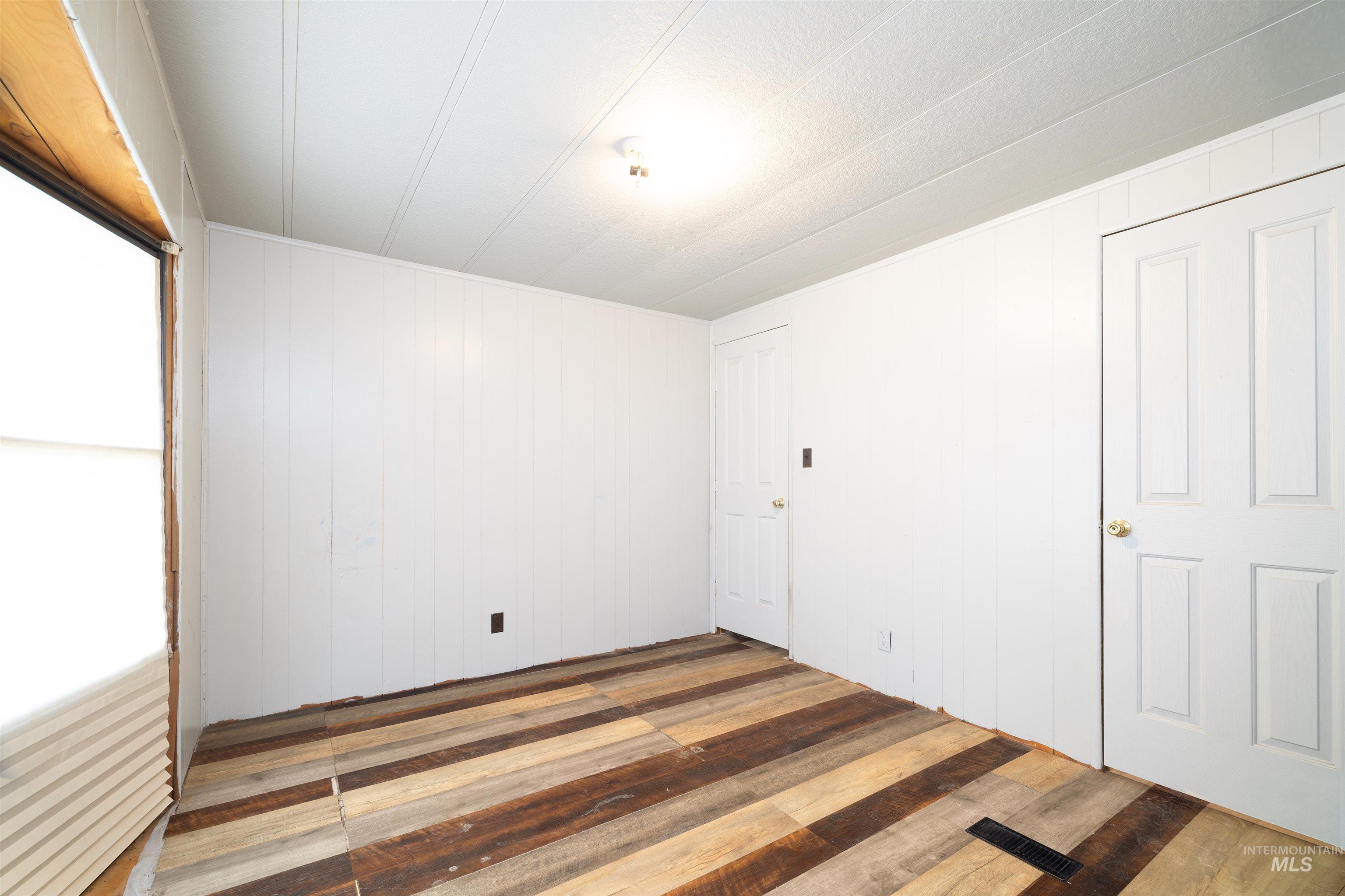 Unfurnished bedroom featuring wood-type flooring and wood walls