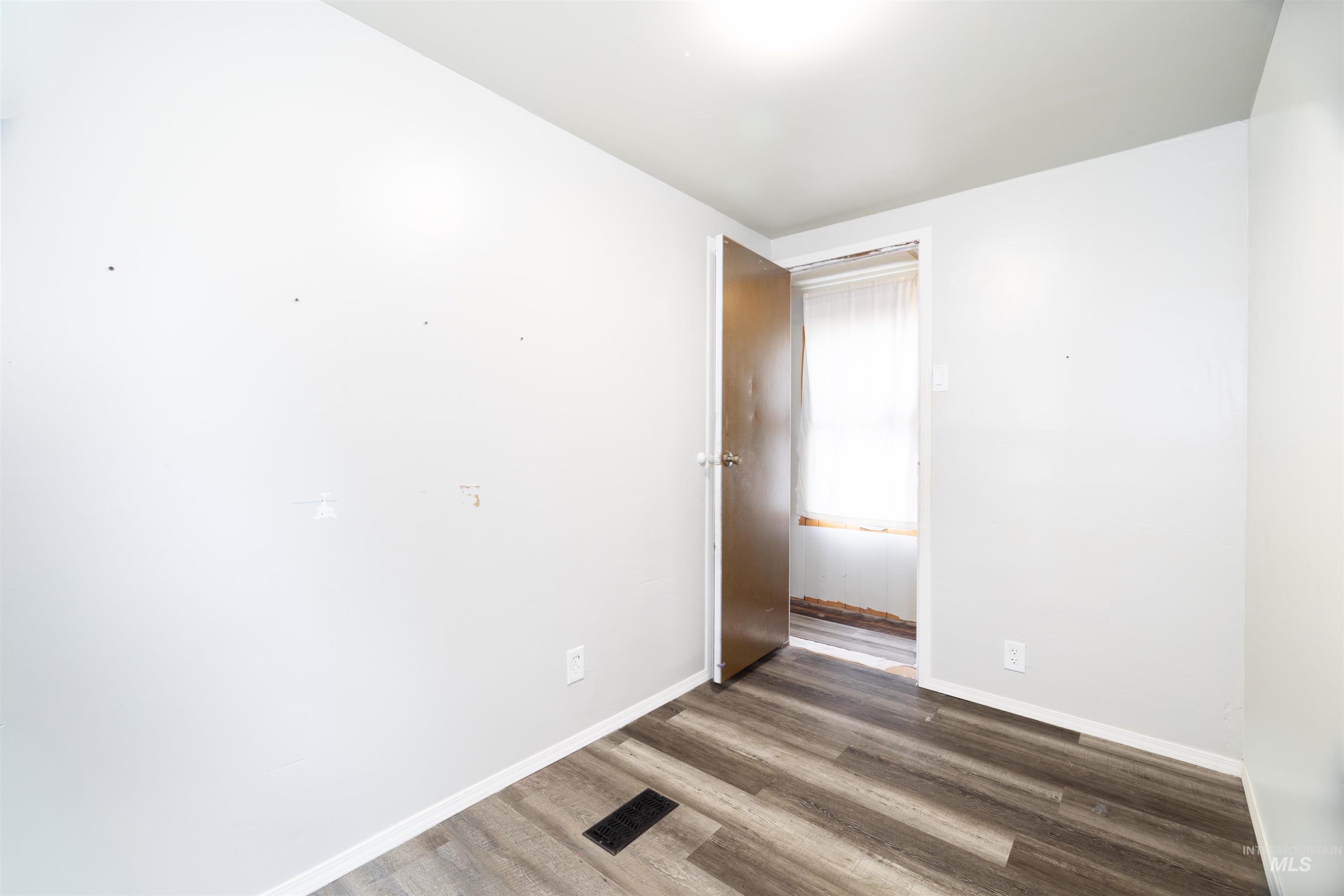 Unfurnished room with dark wood-style flooring and baseboards