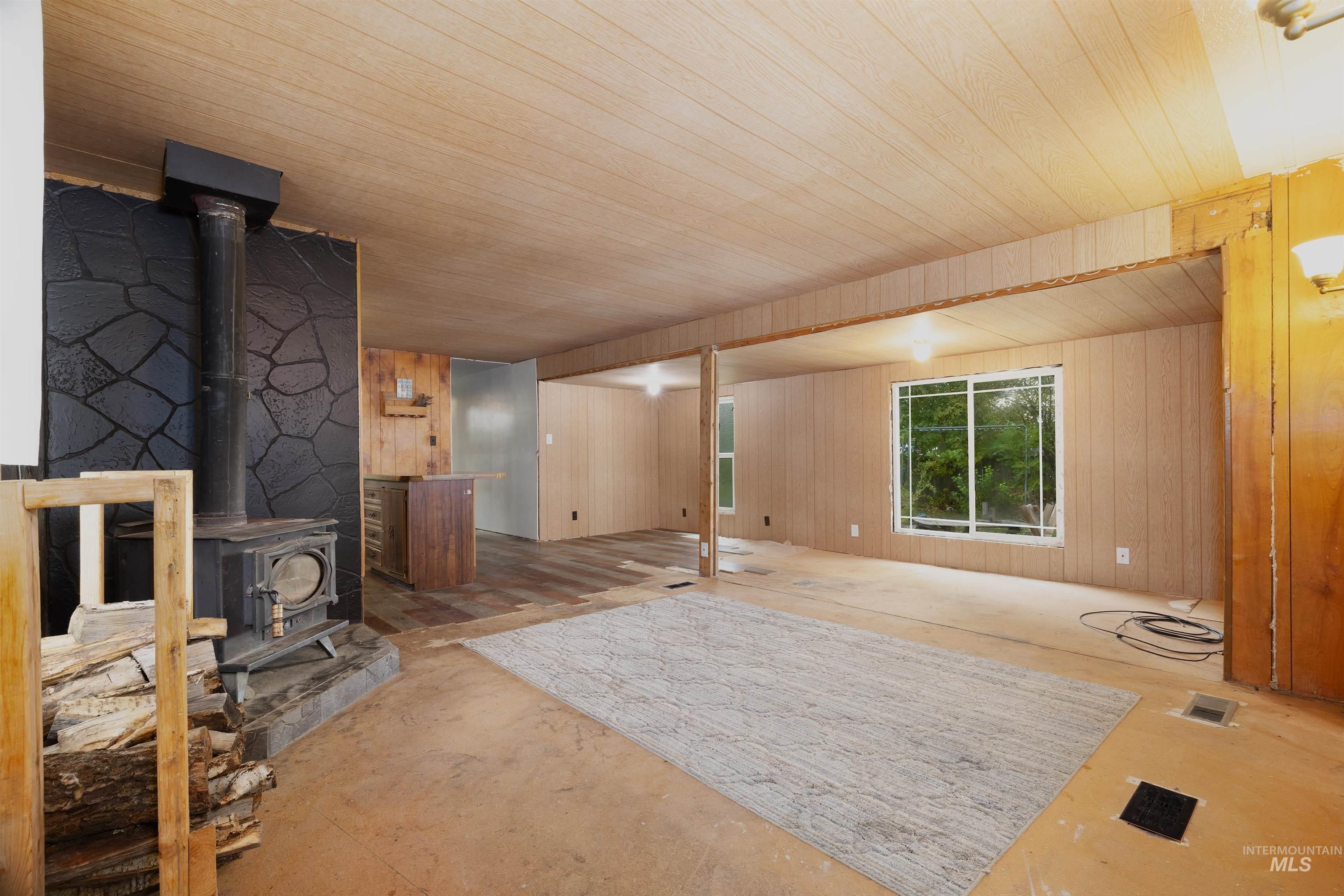 Unfurnished living room with a wood stove and wooden walls
