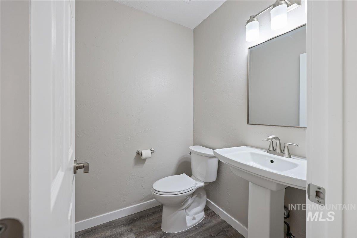 Half bath featuring dark wood-style floors and a textured wall