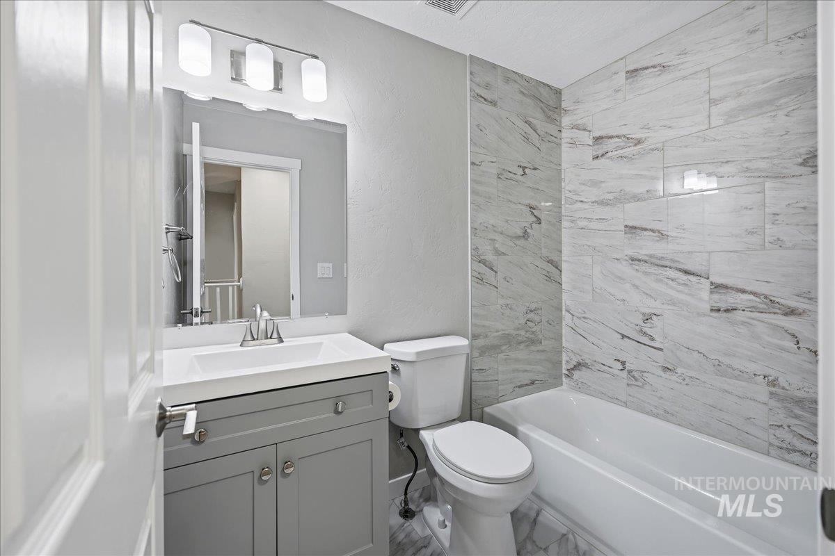 Full bathroom featuring vanity, a textured wall, and bathing tub / shower combination