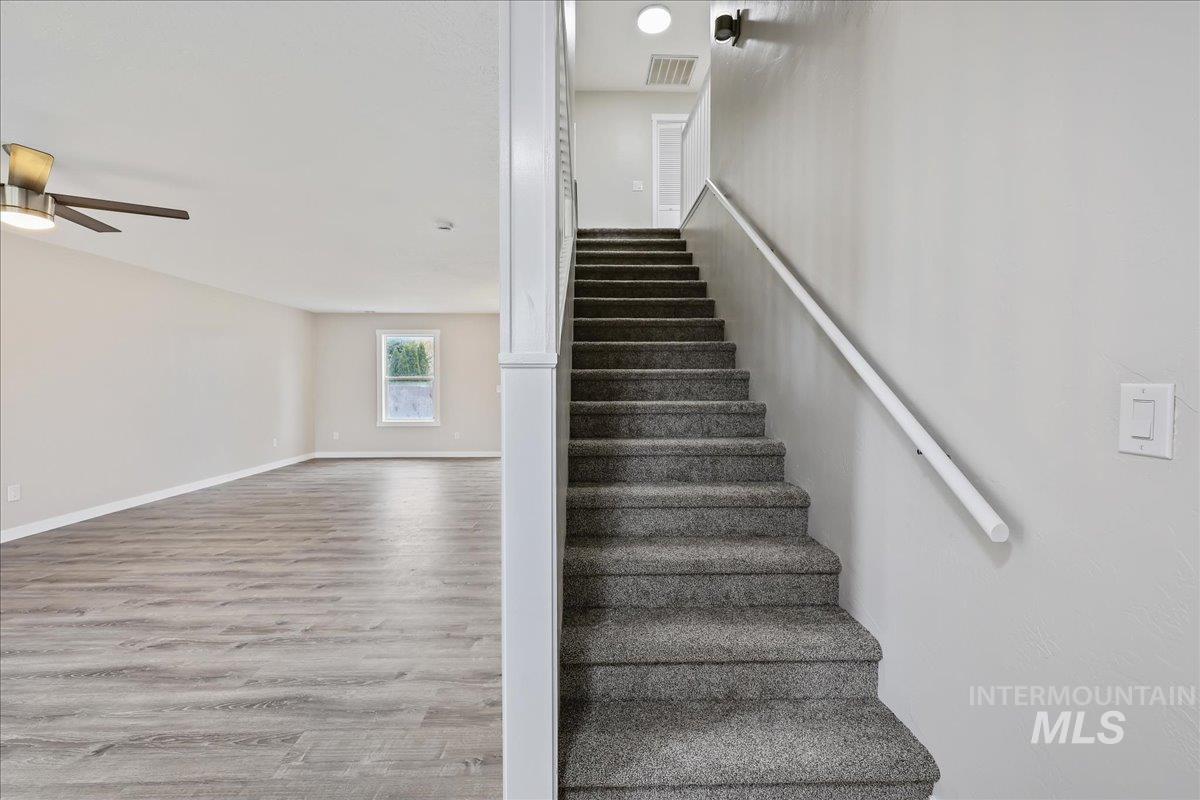 Staircase featuring wood finished floors and a ceiling fan