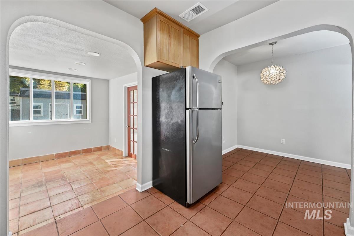 Kitchen featuring freestanding refrigerator, arched walkways, a chandelier, and hanging light fixtures