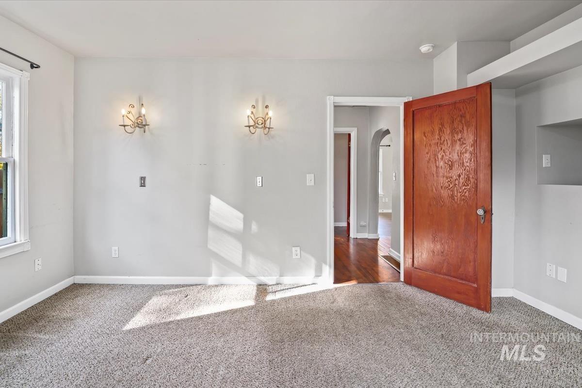 Carpeted spare room featuring baseboards and arched walkways