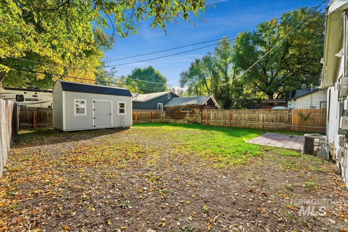 Fenced backyard with a storage shed and a patio