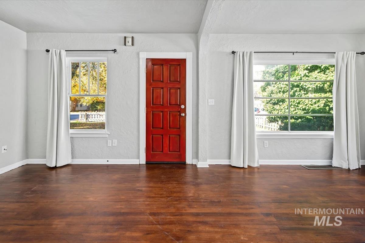 Entrance foyer featuring a textured wall, dark wood-type flooring, healthy amount of natural light, and a textured ceiling