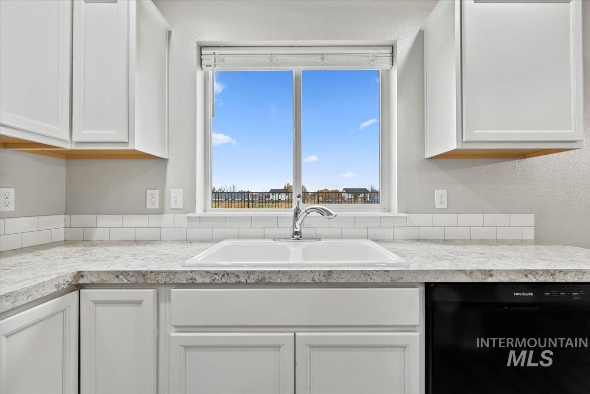 Kitchen featuring dishwasher, white cabinetry, and light countertops