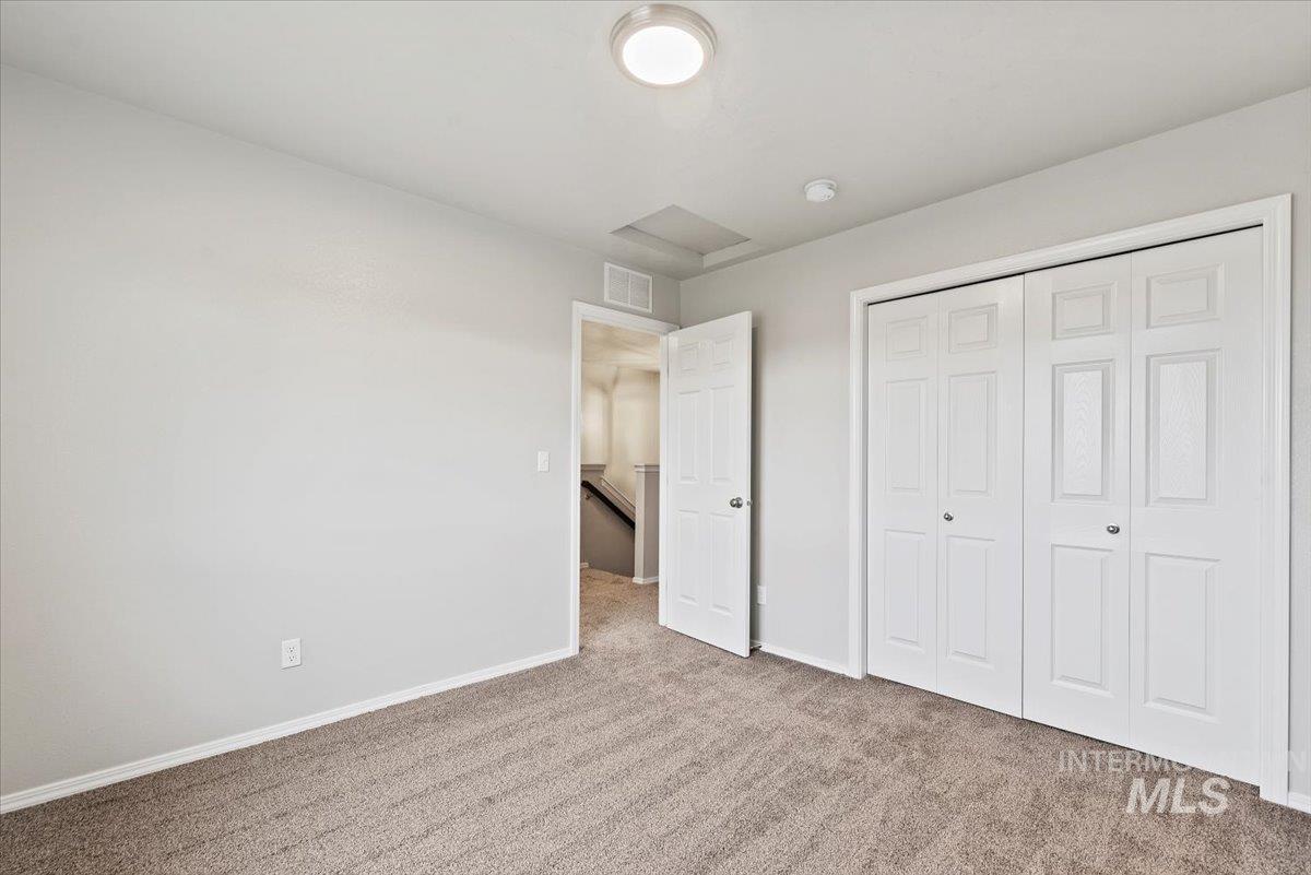 Unfurnished bedroom featuring carpet, a closet, and attic access