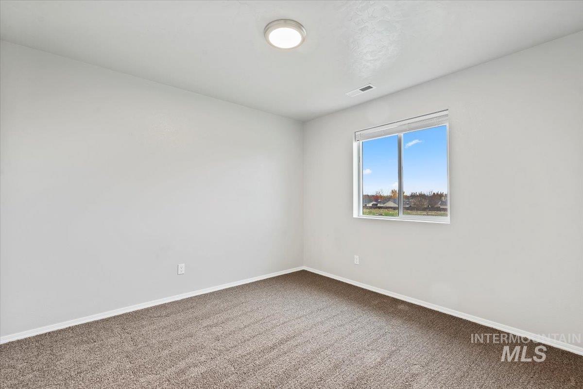 Carpeted spare room featuring baseboards