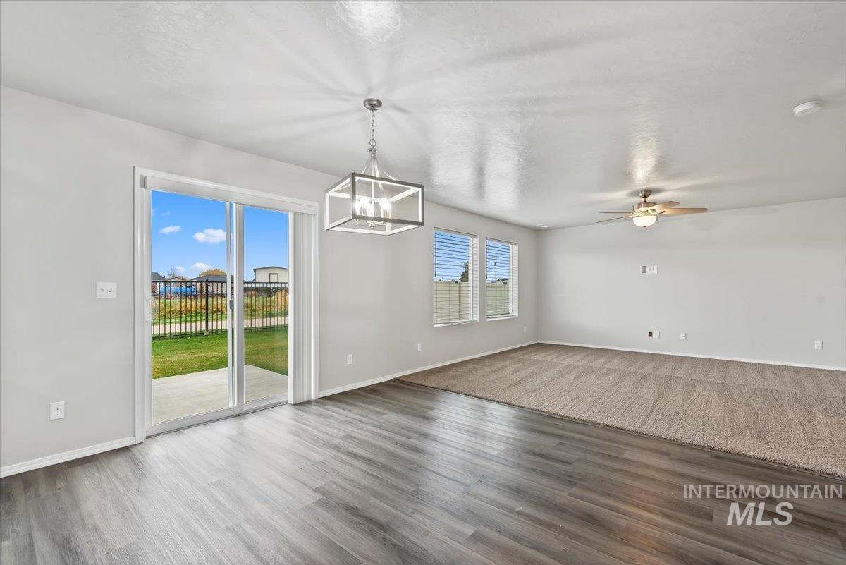 Unfurnished dining area featuring wood finished floors, ceiling fan, a chandelier, and a textured ceiling