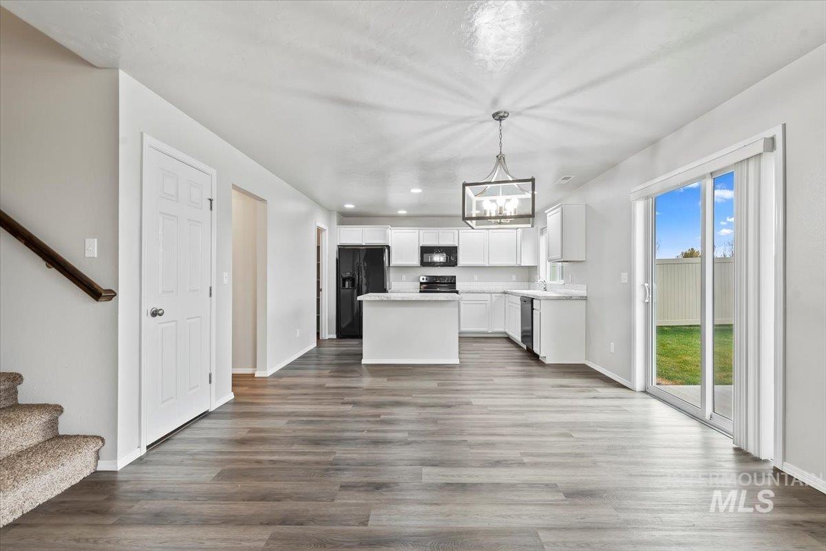Kitchen with light countertops, open floor plan, a center island, white cabinetry, and black appliances