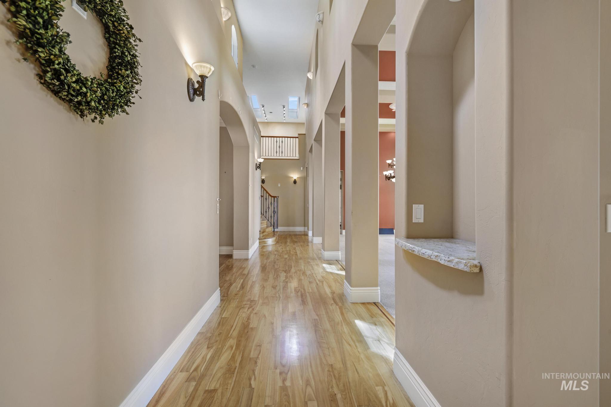 Corridor with arched walkways and light wood-type flooring