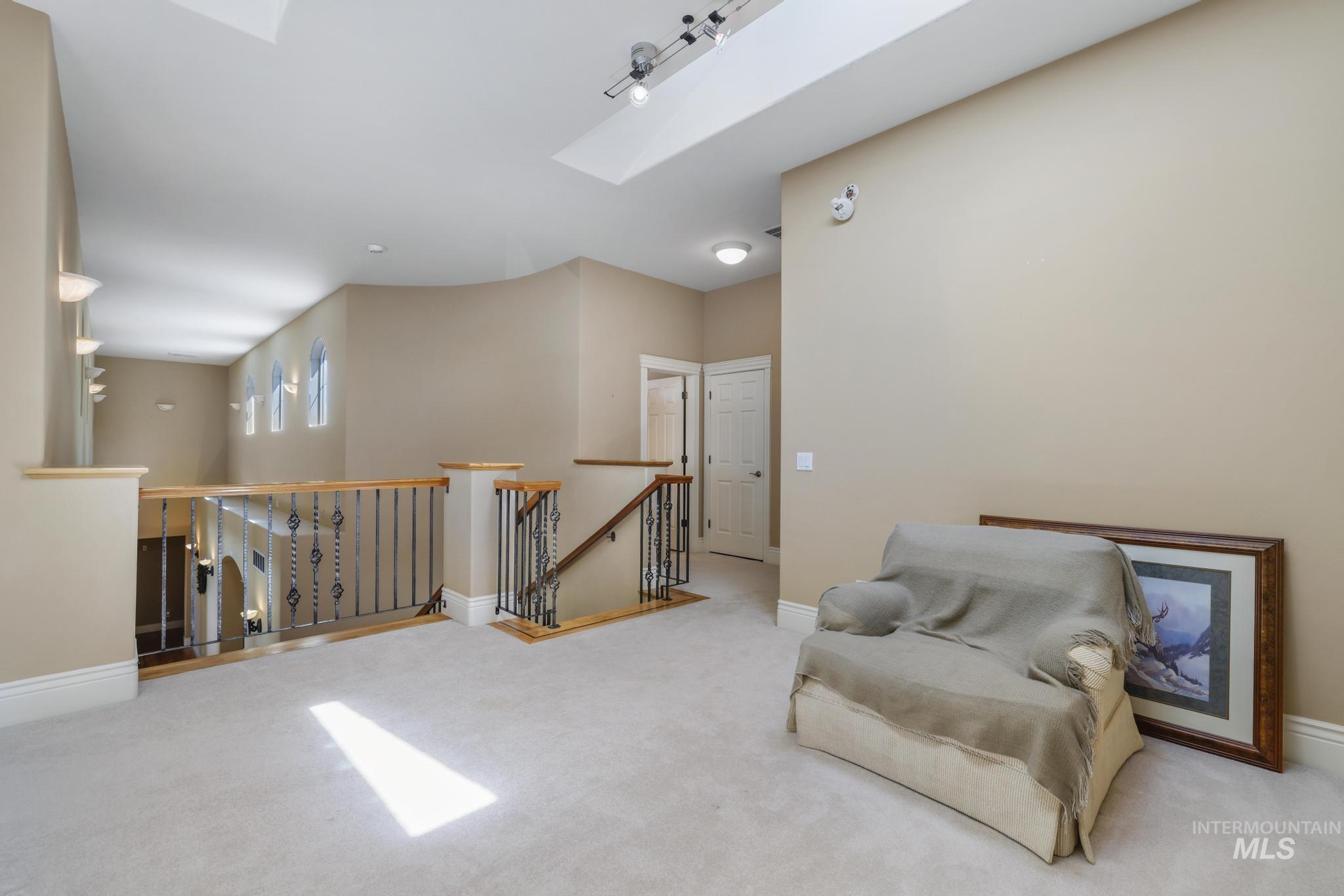 Living area featuring an upstairs landing, a skylight, and carpet