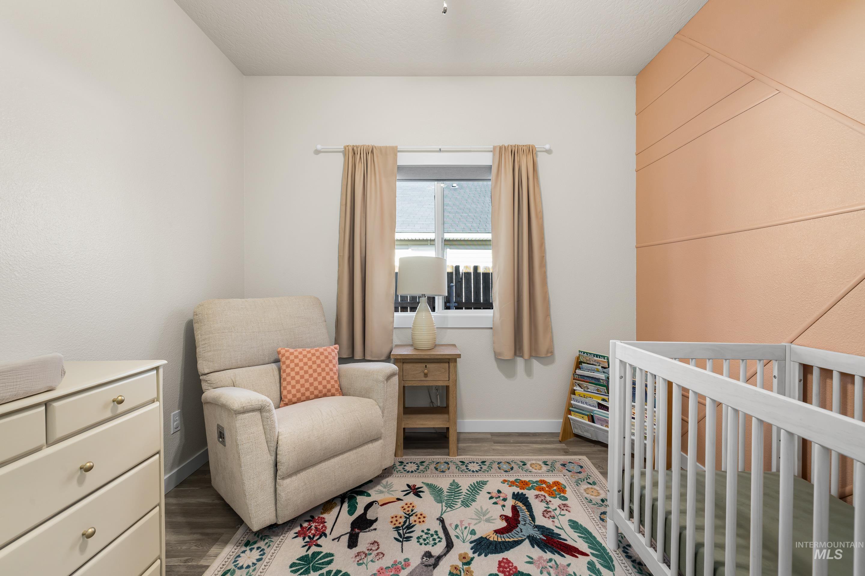 Bedroom with a crib and wood finished floors
