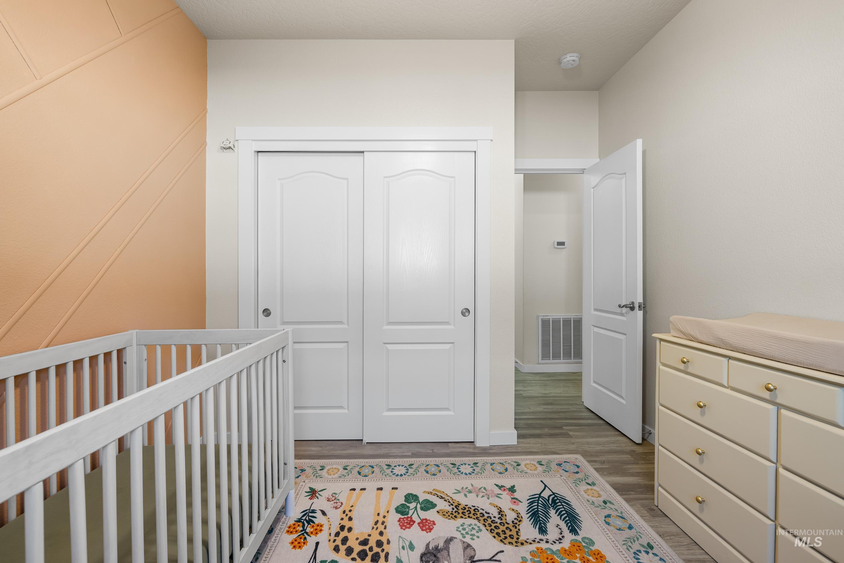 Bedroom featuring a closet, light wood-type flooring, and a crib