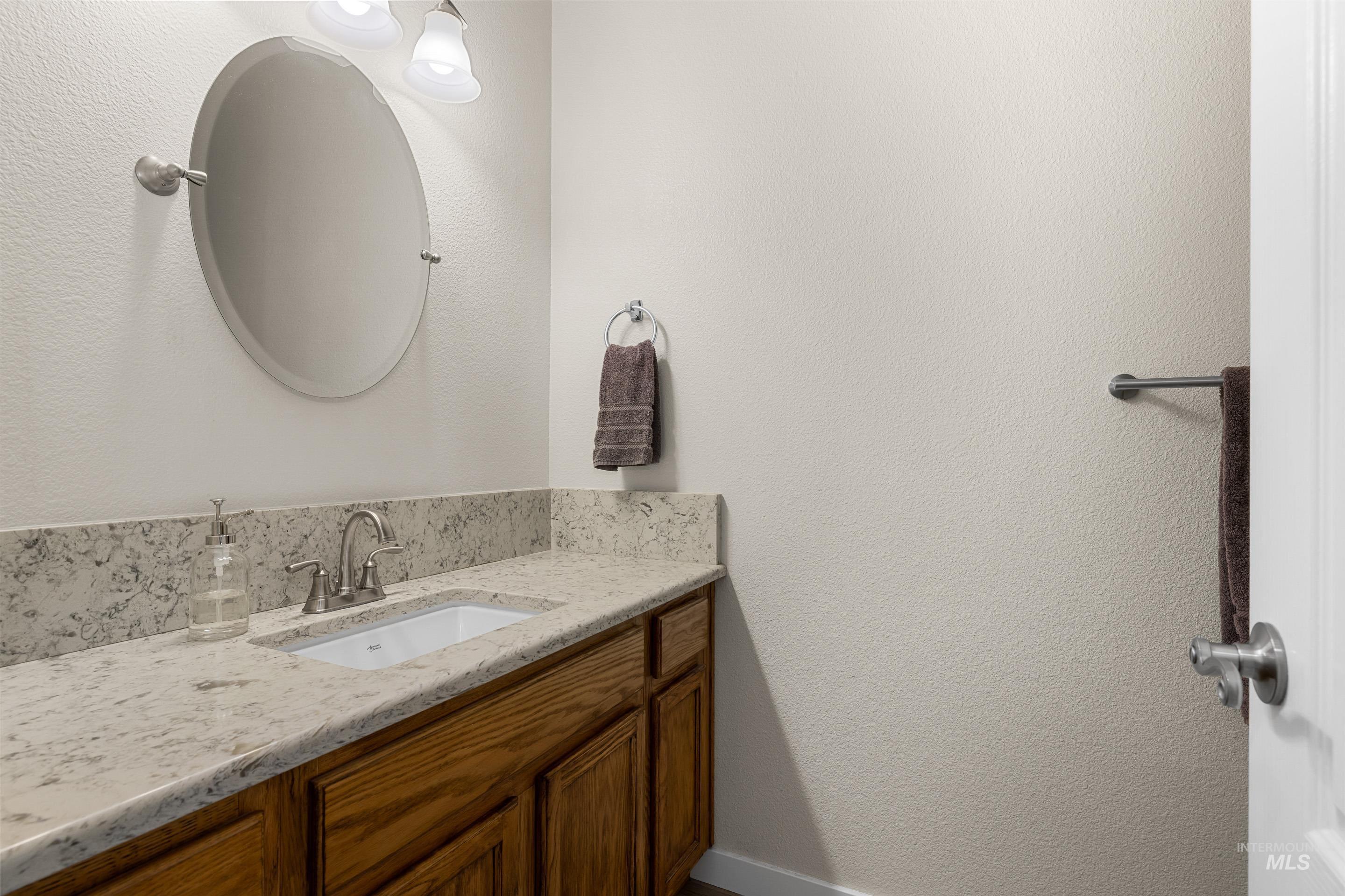 Bathroom featuring a textured wall and vanity
