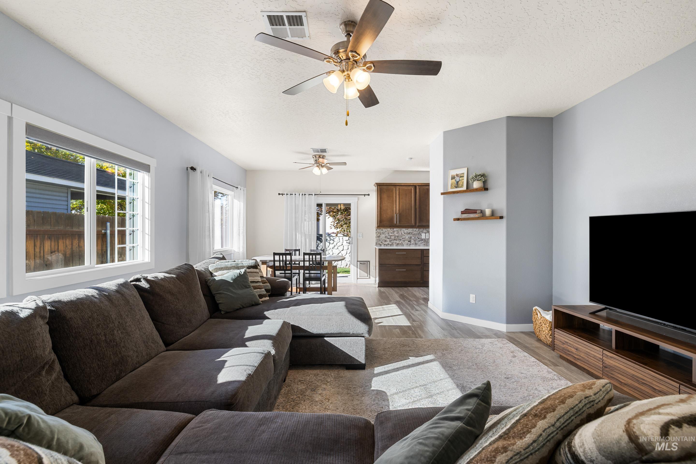 Living area with light wood-style floors, a textured ceiling, and ceiling fan