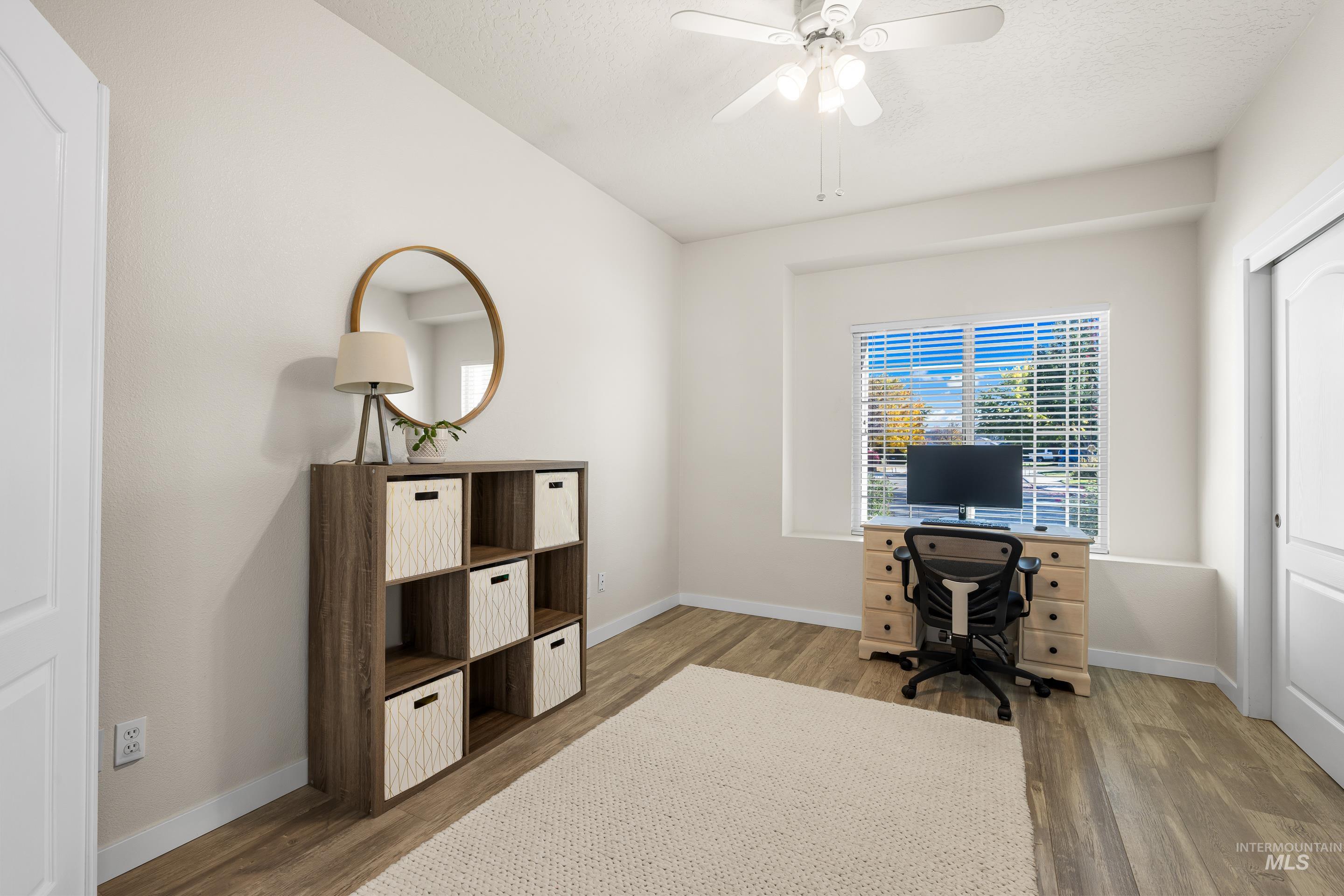 Office with light wood-style floors and a ceiling fan