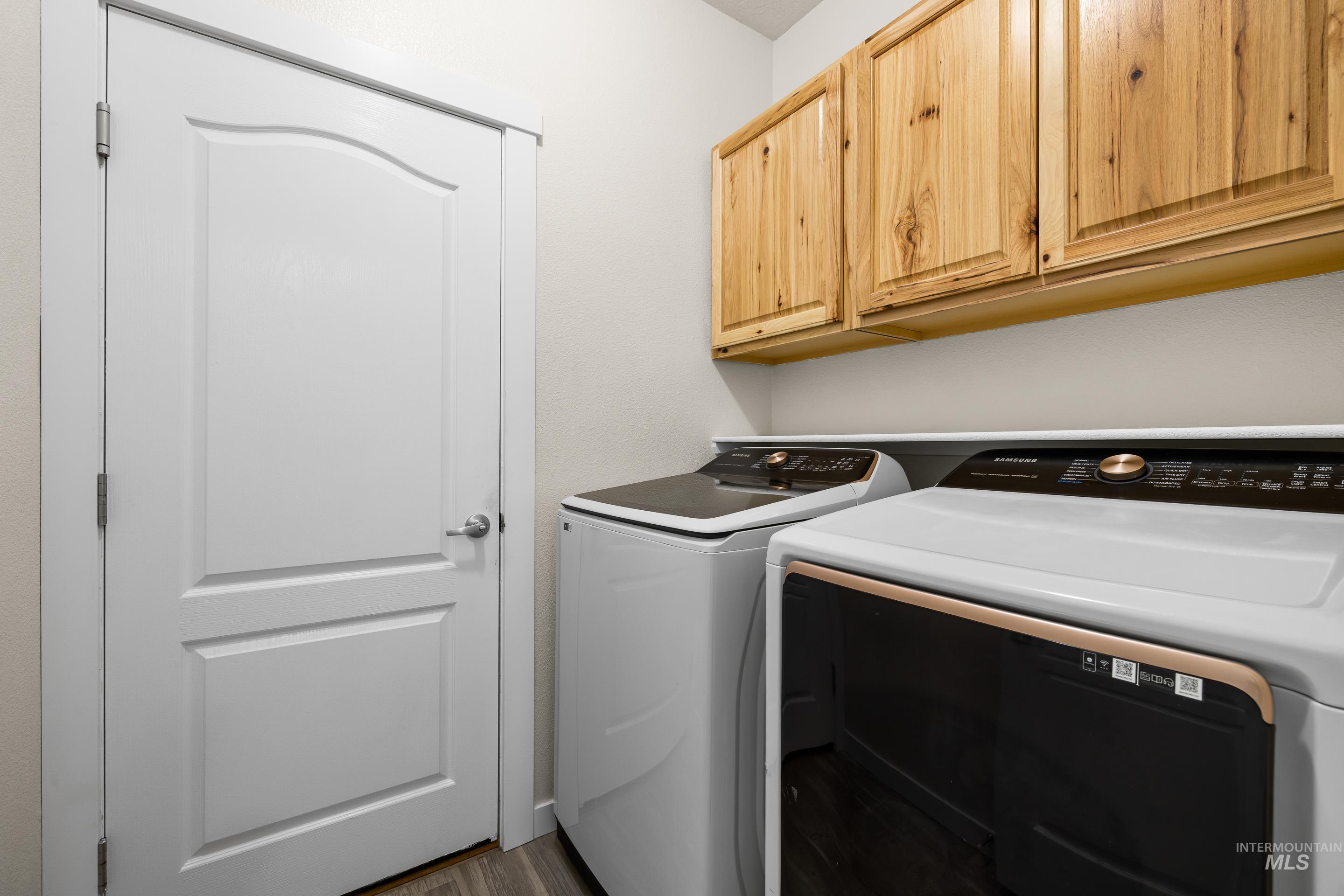 Laundry area featuring independent washer and dryer, cabinet space, and dark wood-type flooring