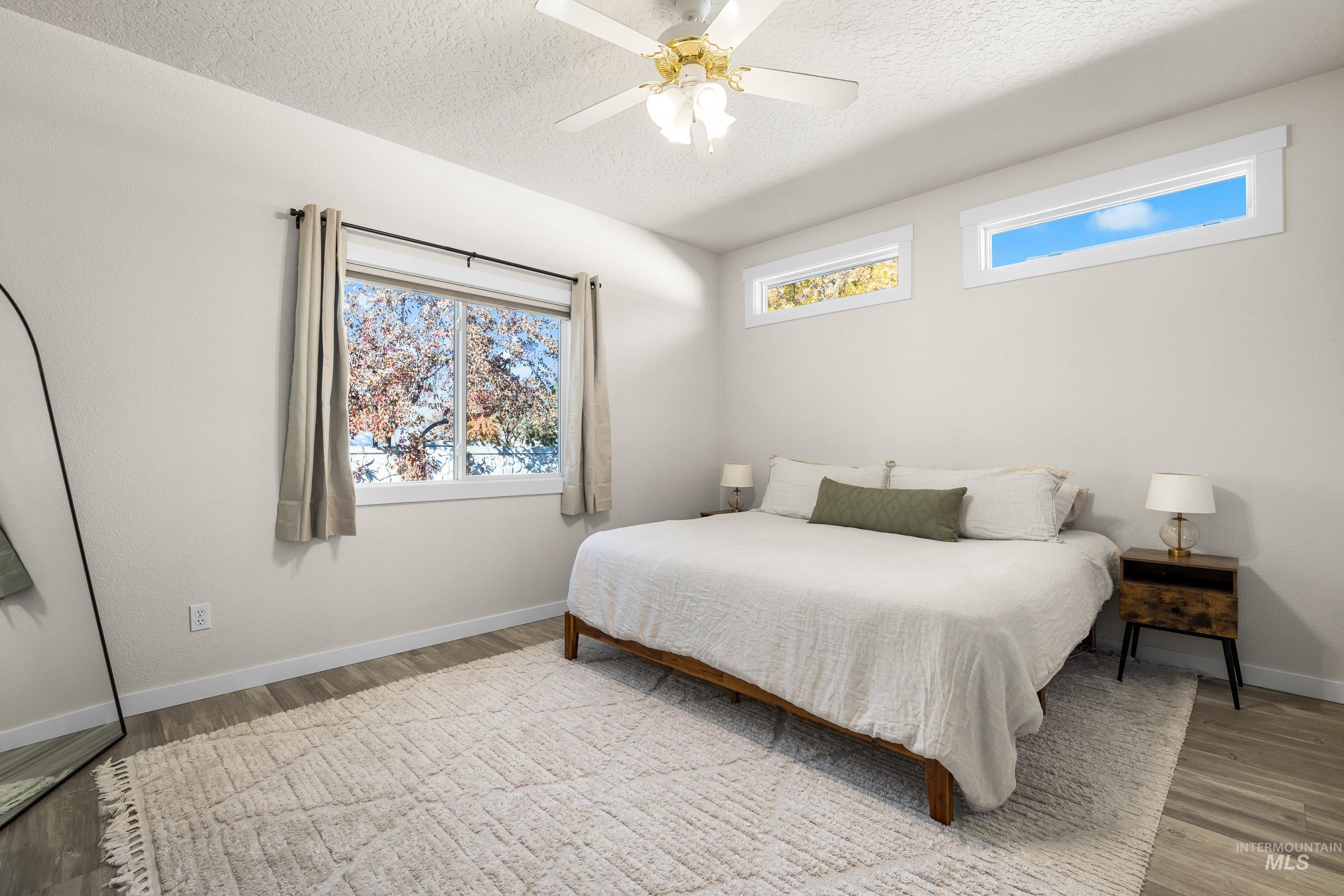 Bedroom with a textured ceiling, wood finished floors, and ceiling fan