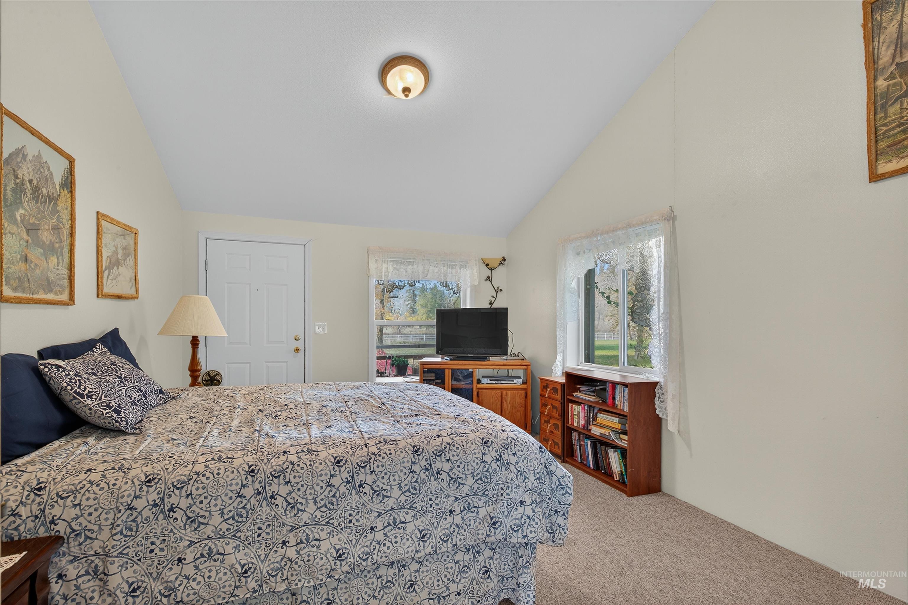 Bedroom with light colored carpet and vaulted ceiling