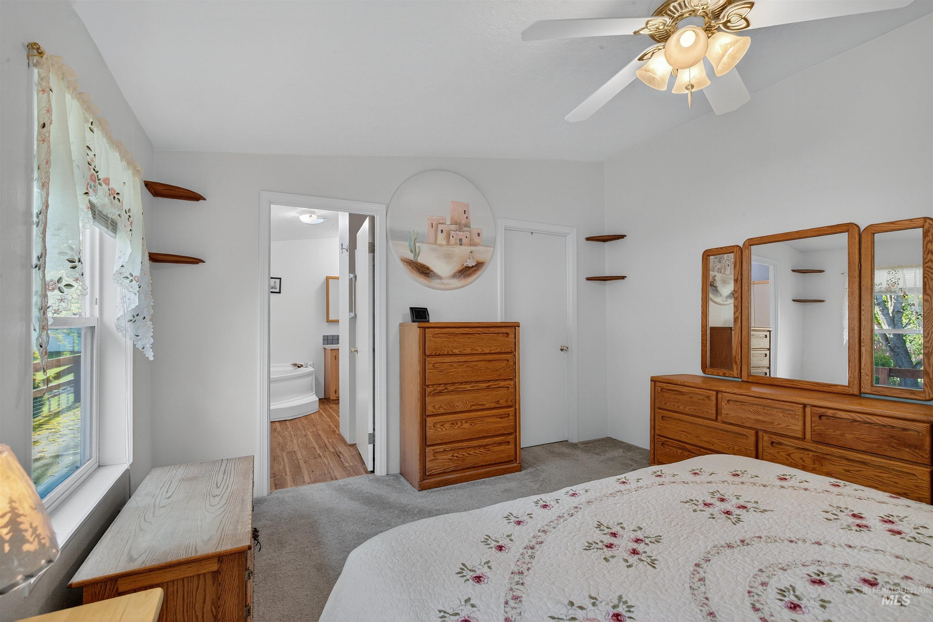 Bedroom featuring light colored carpet, a ceiling fan, and ensuite bathroom