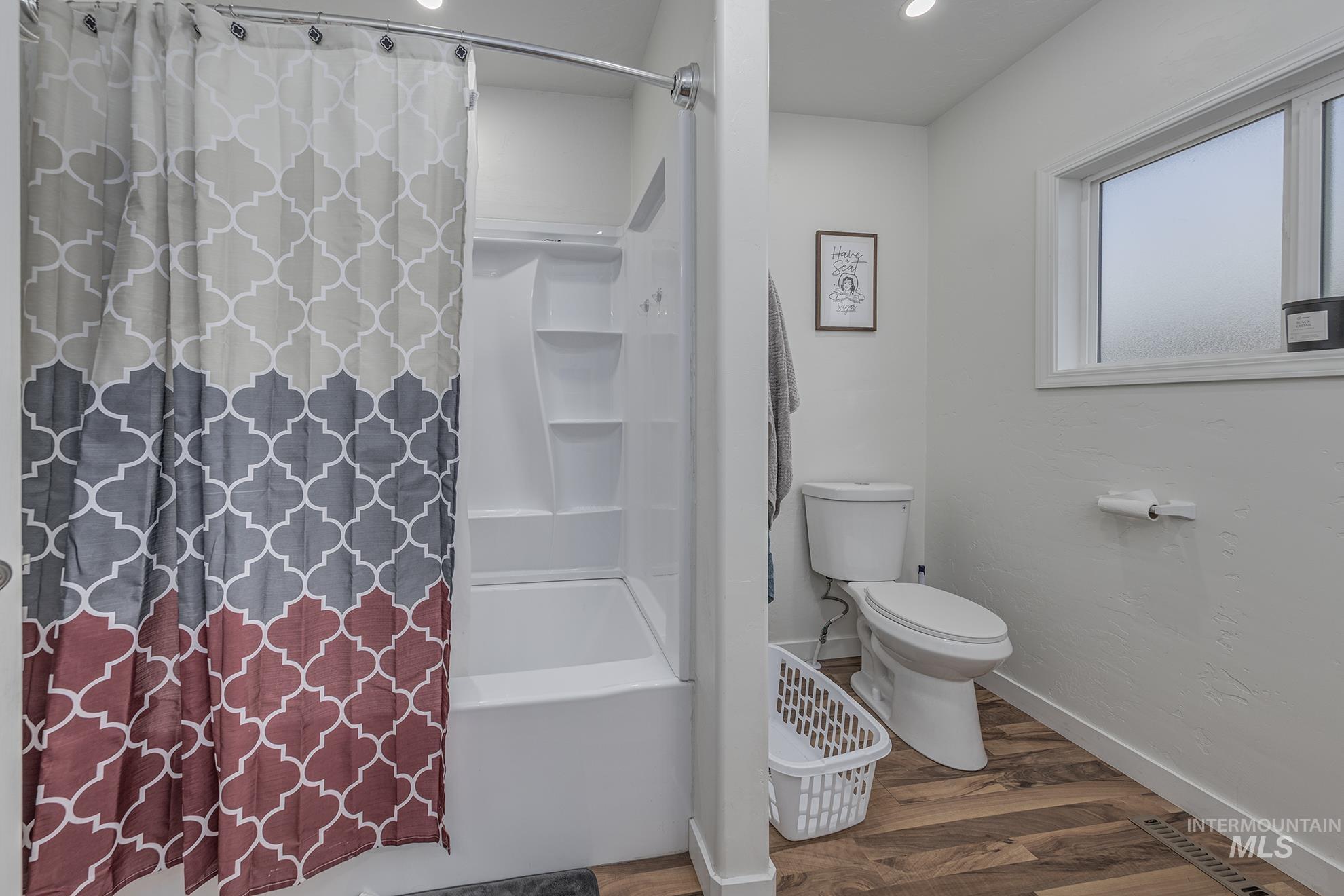 Full bath featuring wood finished floors, shower / tub combo with curtain, and recessed lighting