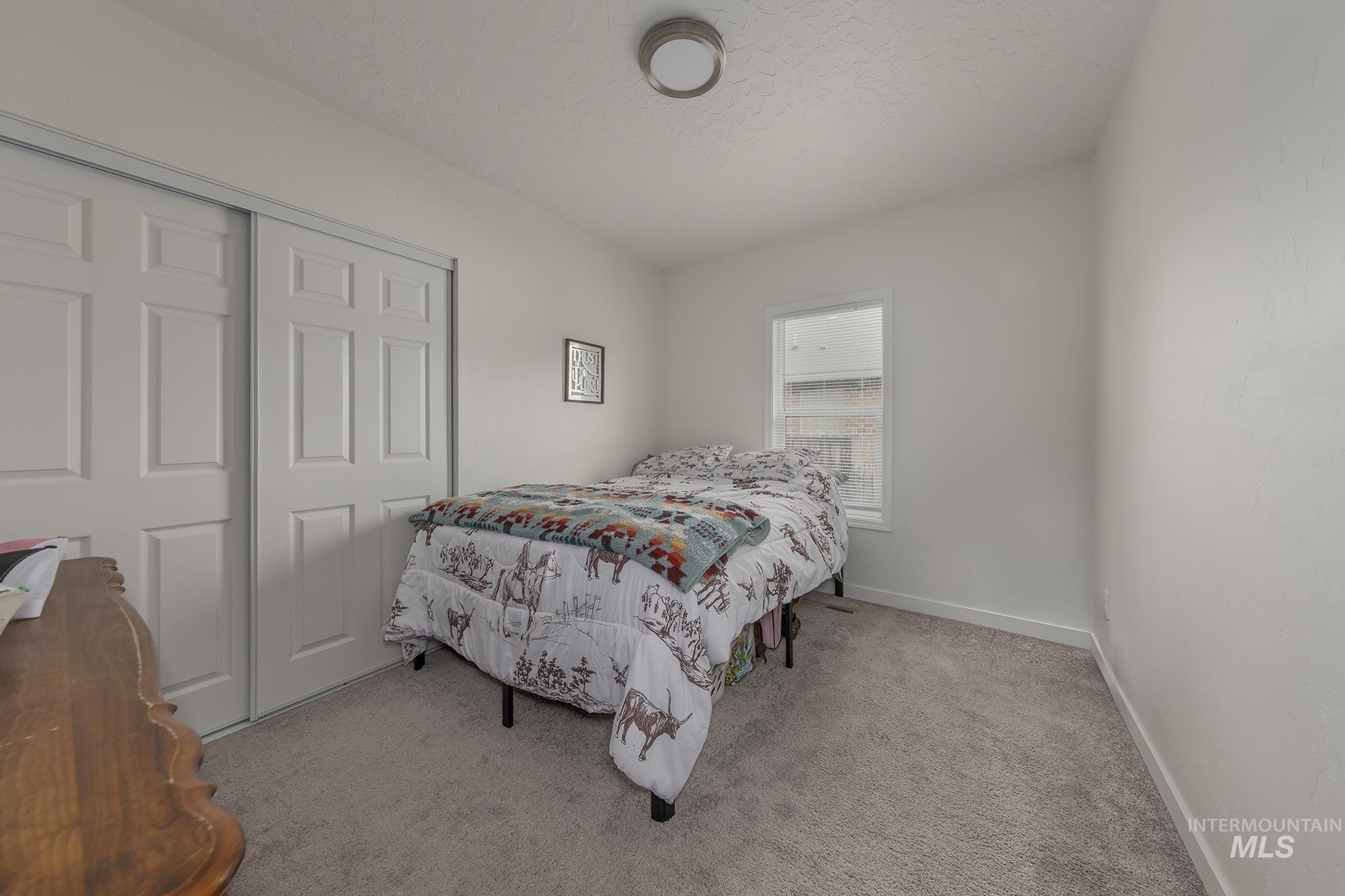 Carpeted bedroom featuring a closet and a textured ceiling