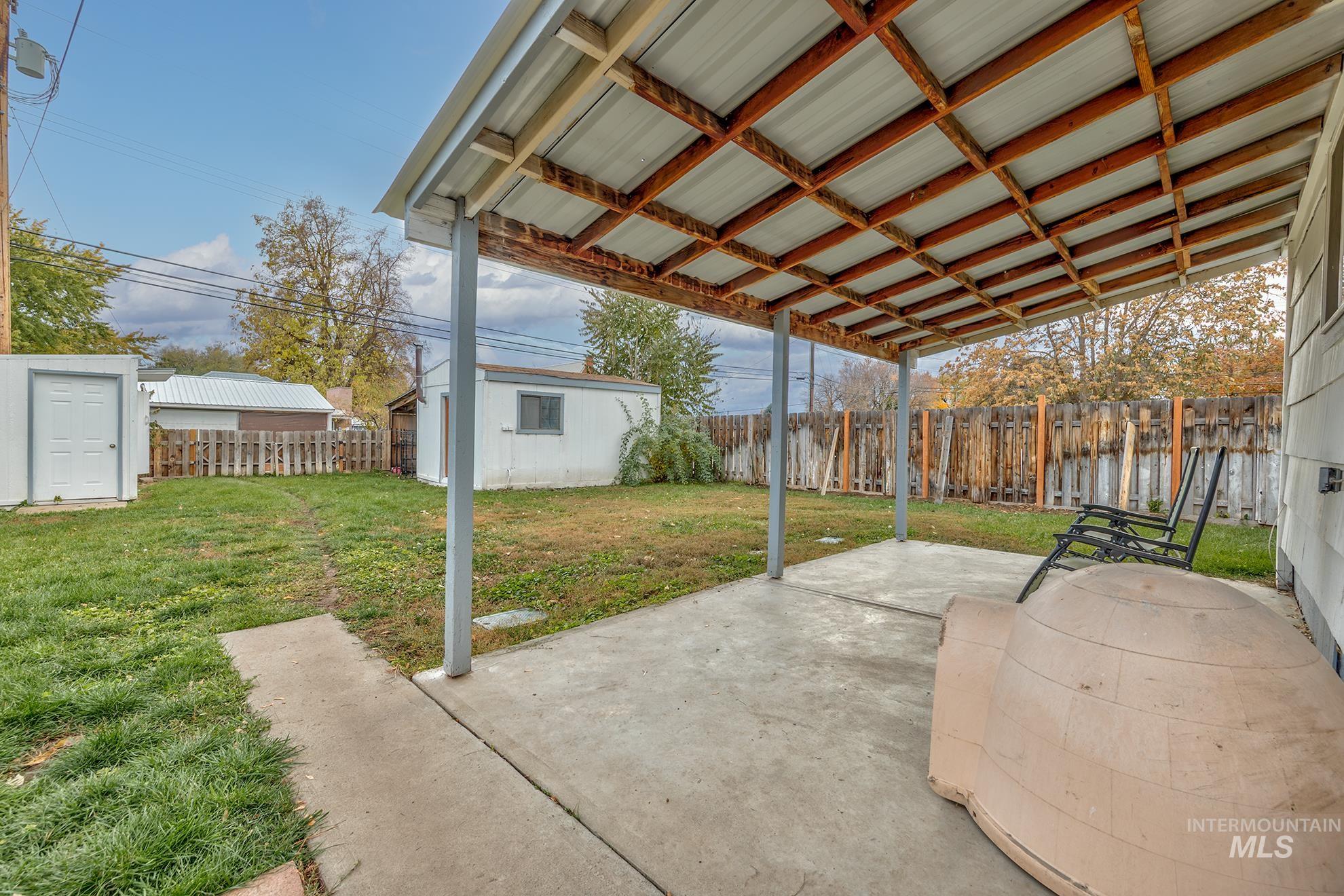 Fenced backyard featuring an outbuilding and a patio