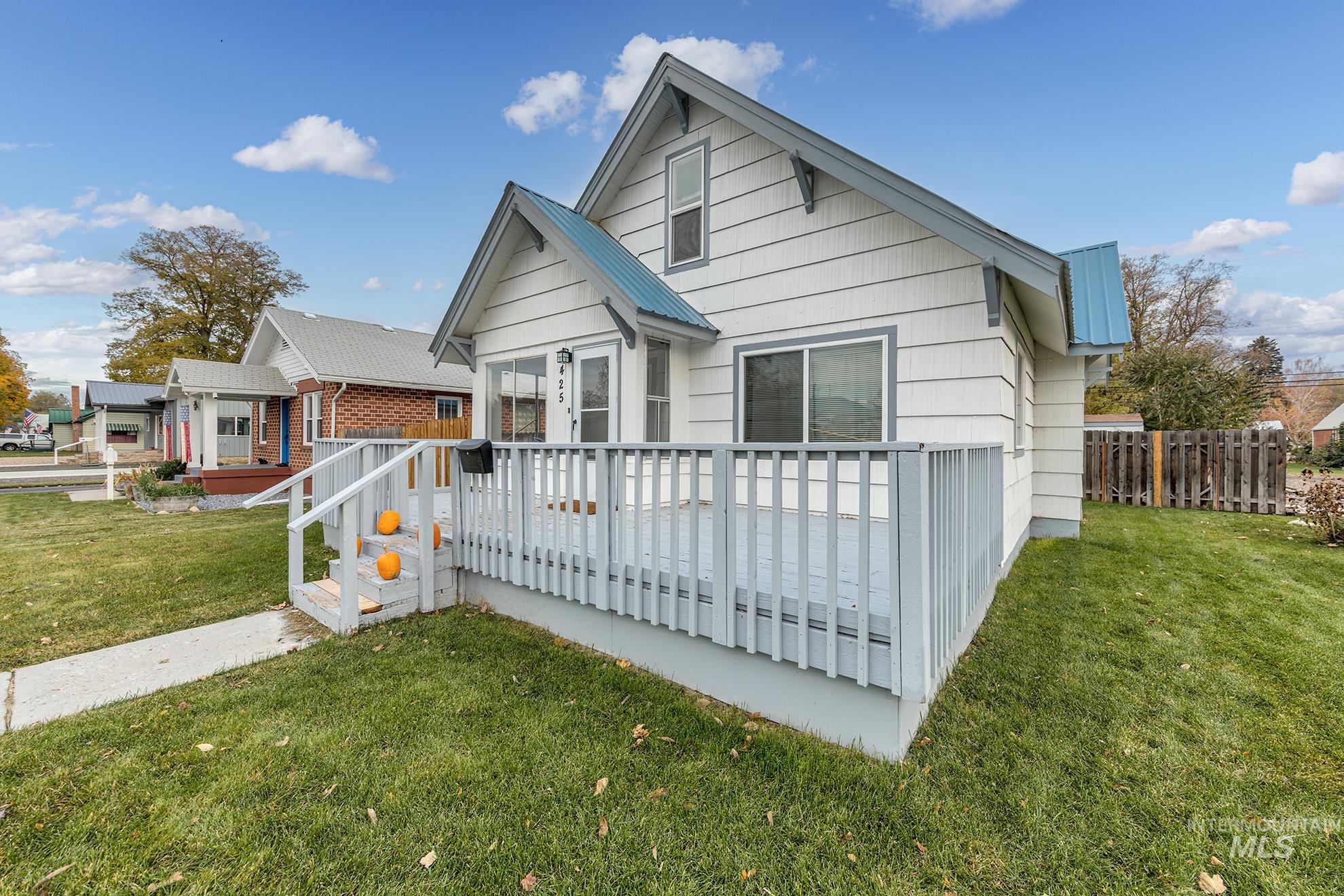 View of front of home featuring a wooden deck, a front yard, and a metal roof