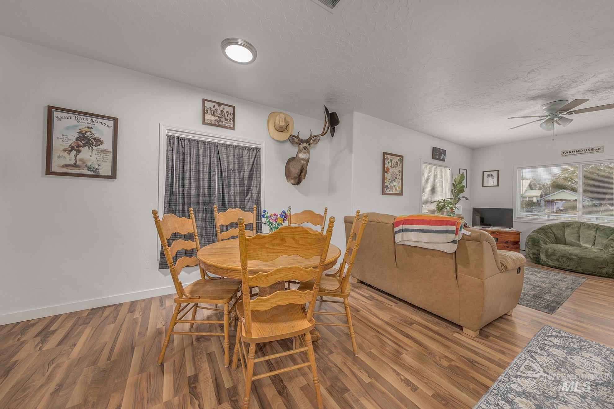 Dining room featuring wood finished floors, a ceiling fan, and a textured ceiling
