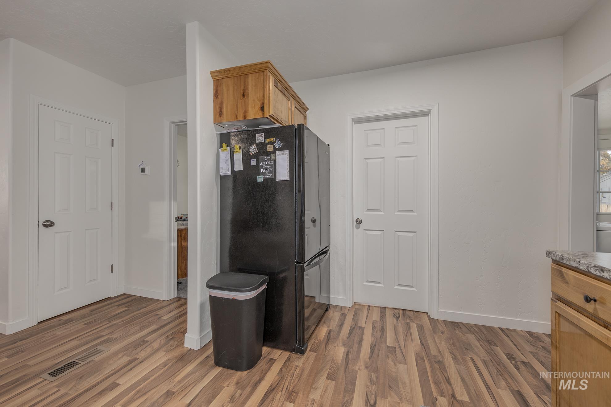 Kitchen with brown cabinetry, freestanding refrigerator, and light wood-type flooring