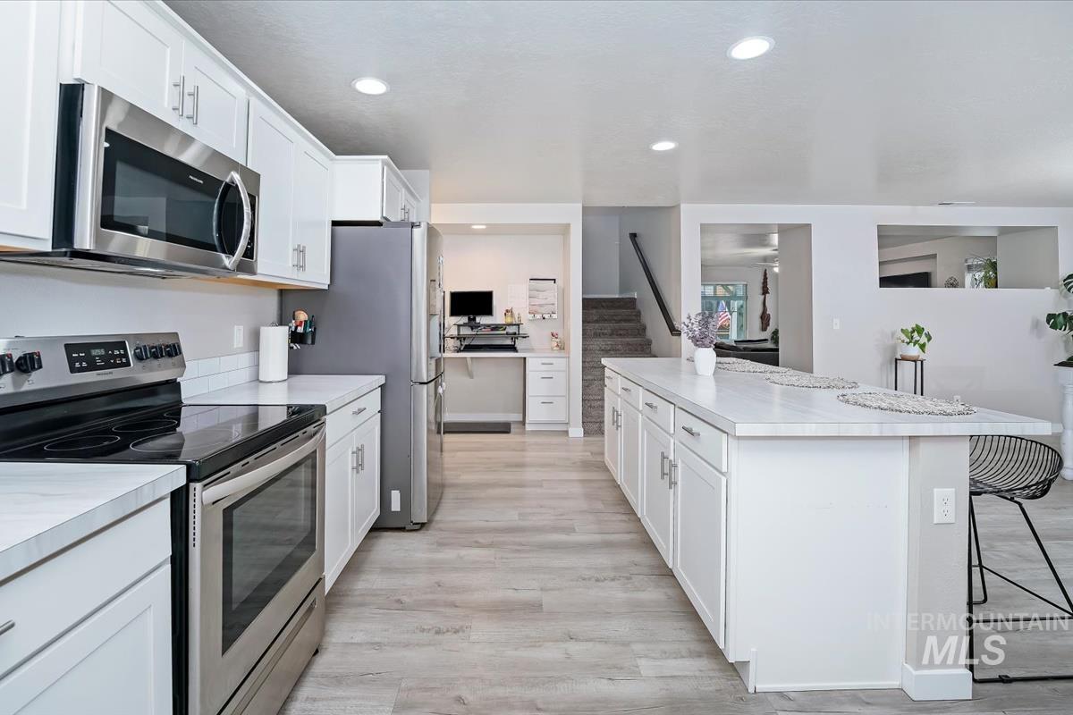 Kitchen featuring appliances with stainless steel finishes, light countertops, white cabinetry, and recessed lighting