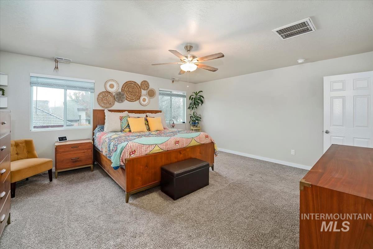 Bedroom with carpet, multiple windows, and a ceiling fan