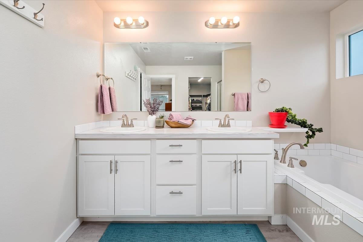 Bathroom featuring double vanity, a garden tub, and a walk in closet