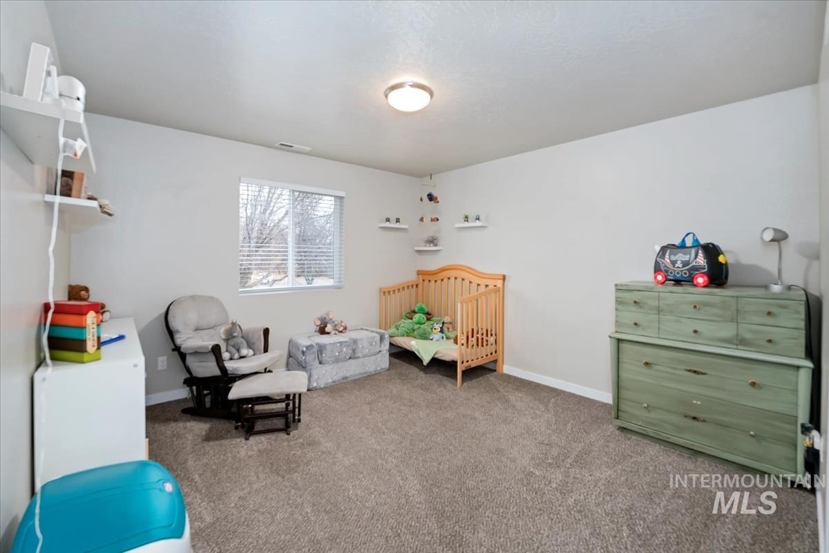 Carpeted bedroom featuring a nursery area and baseboards