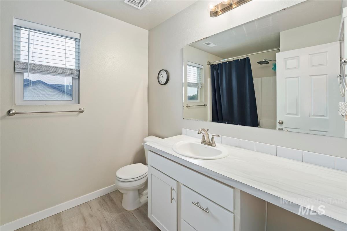 Bathroom with light wood-type flooring, a shower with curtain, and vanity