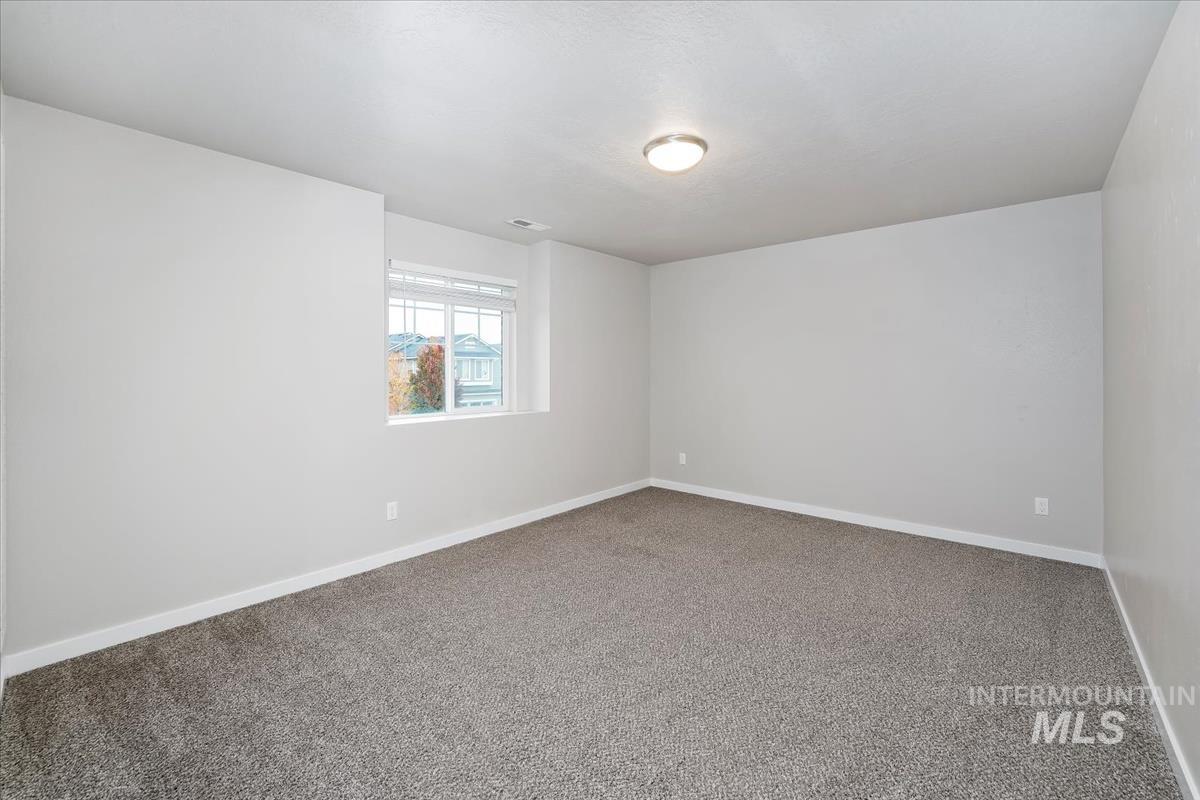 Carpeted spare room featuring baseboards