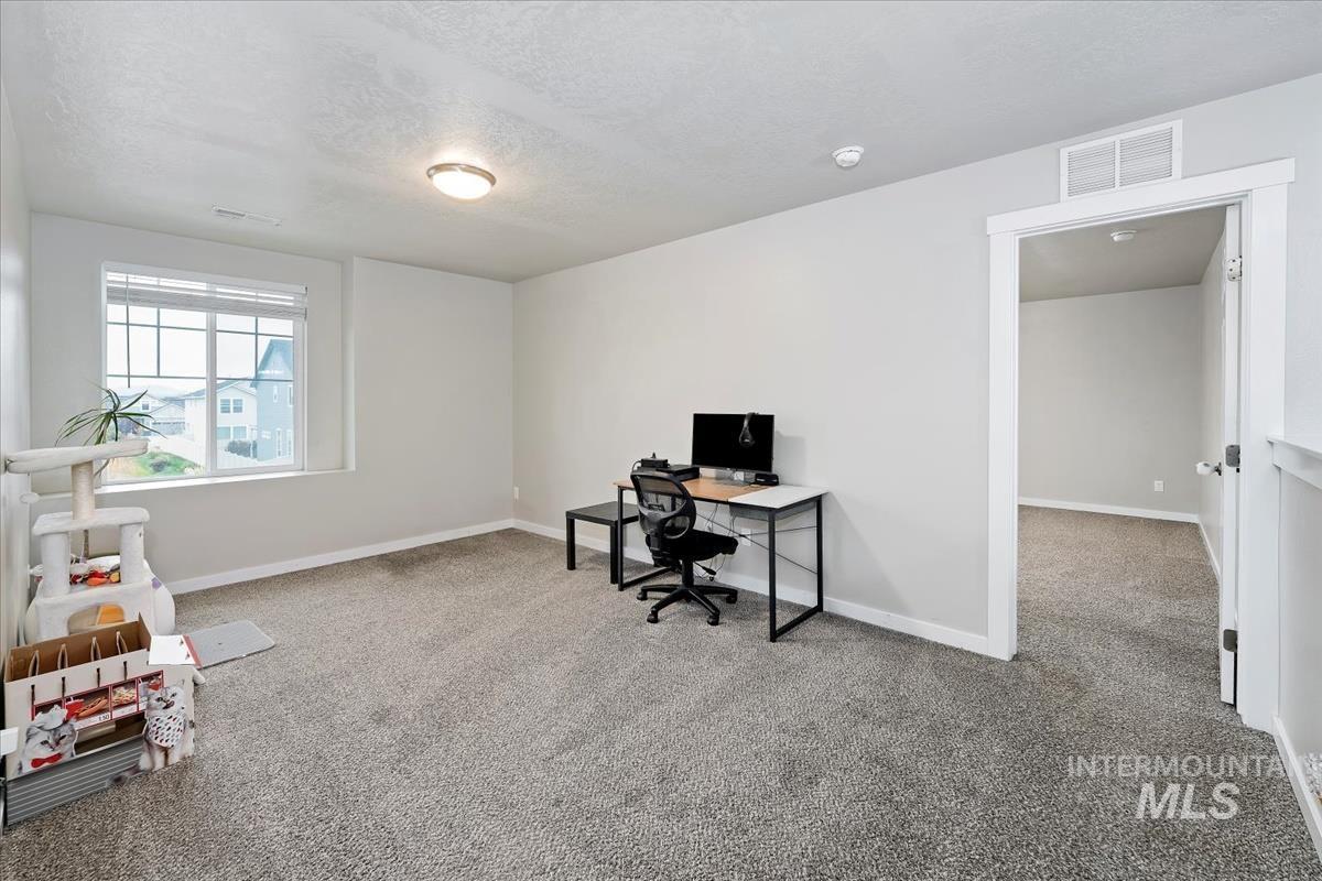 Home office with light carpet and a textured ceiling