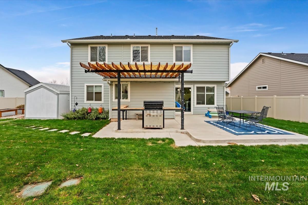Rear view of house with a pergola, a patio, and a shed