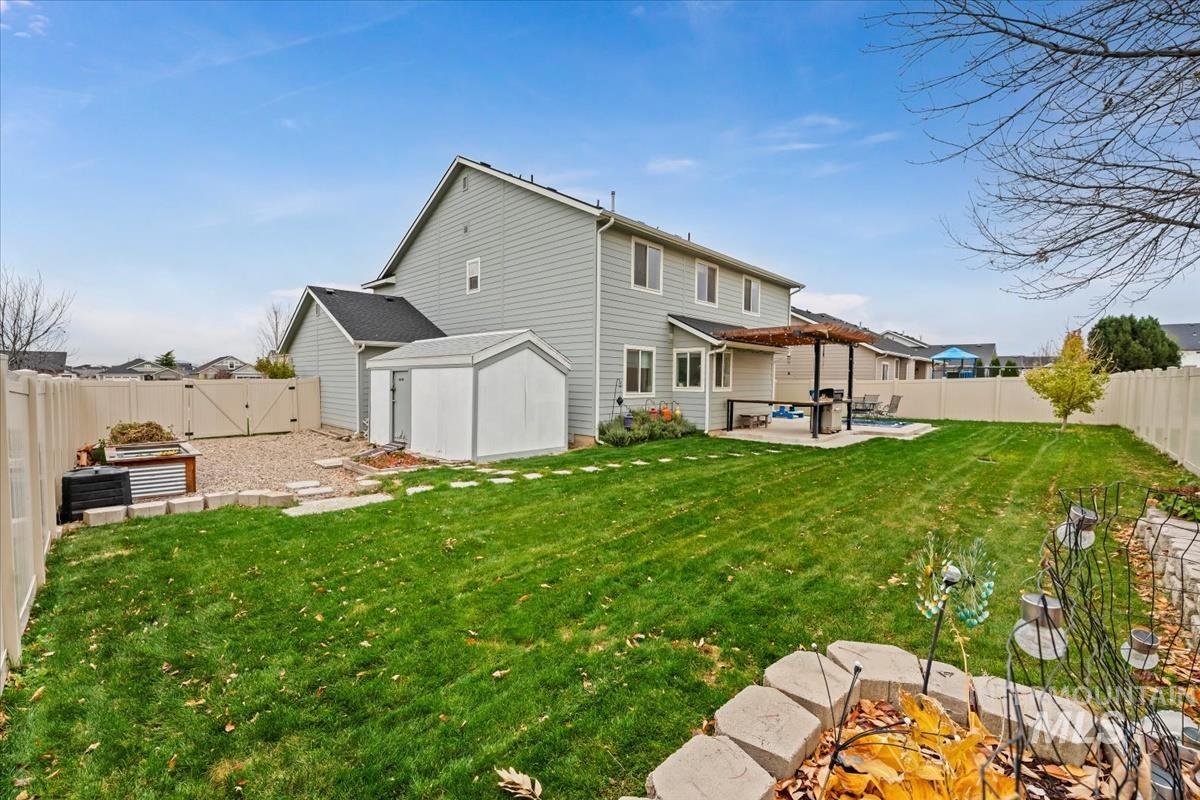 Rear view of house featuring a fenced backyard, a patio, a pergola, and a garden