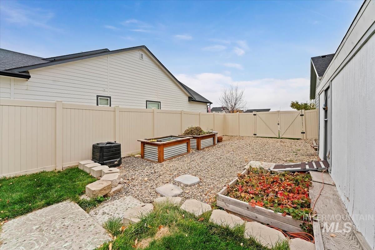 Fenced backyard with a vegetable garden and a gate
