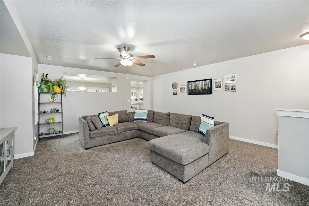 Carpeted living room featuring baseboards and ceiling fan